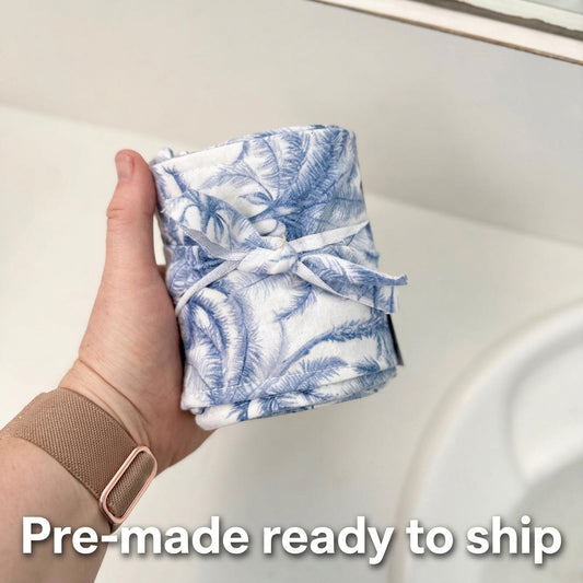 A family cloth toilet roll with snaps, featuring a floral pattern, being used in a bathroom setting.