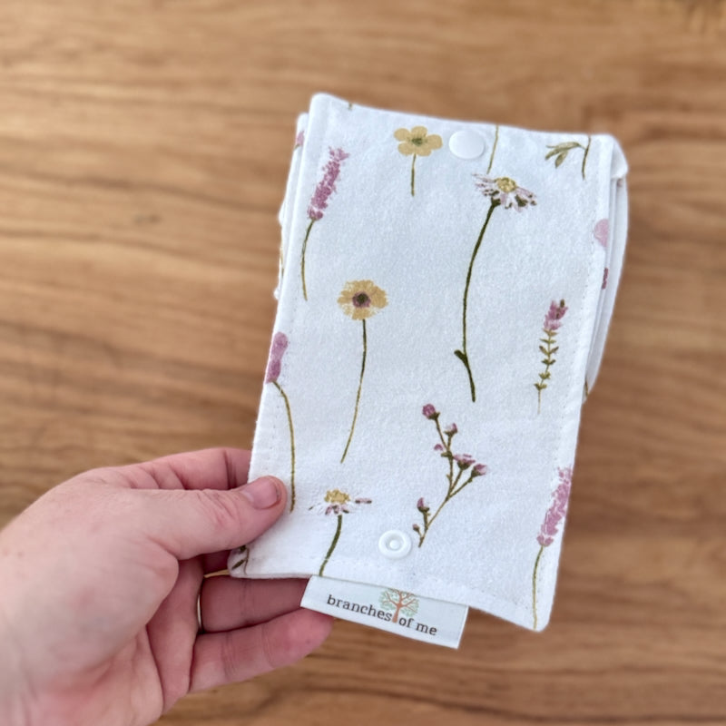 Hand holding a floral-patterned fabric square on a wooden surface