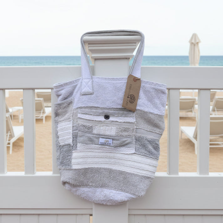Striped bag with a tag on a white railing with a pool and trees in the background